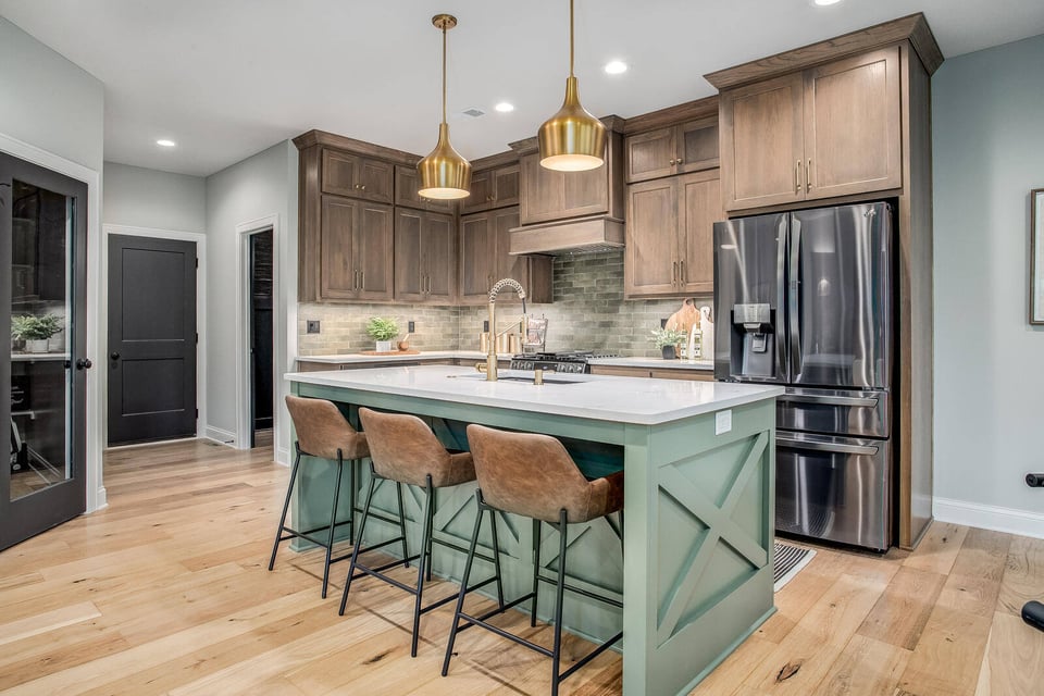 Elegant kitchen remodel featuring a green island, brass pendant lighting, and custom wood cabinetry by Top Shelf Home Builders in Metro Kansas City