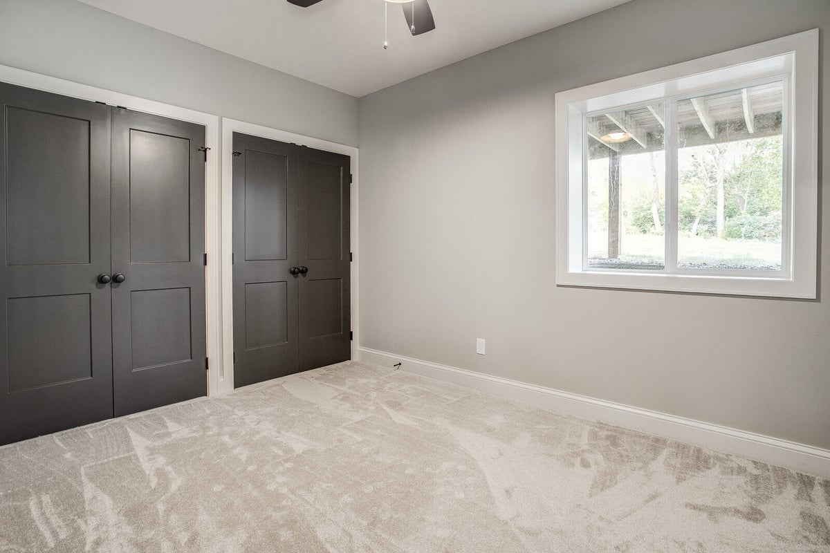 Modern bedroom with black double closet doors and a ceiling fan in a Metro Kansas City home renovation