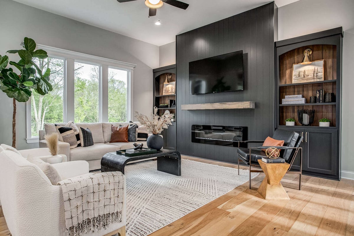 Open-concept living area with a fireplace, modern shelving, and neutral décor by Top Shelf Home Builders