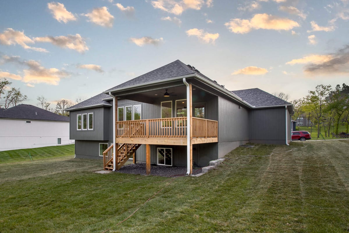 Wide-angle rear view of a custom-renovated home featuring a covered deck and walk-out basement in Metro Kansas City